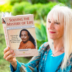 Blonde woman reading Solving the Mystery of Life: Collected Talks and Essays by Paramahansa Yogananda